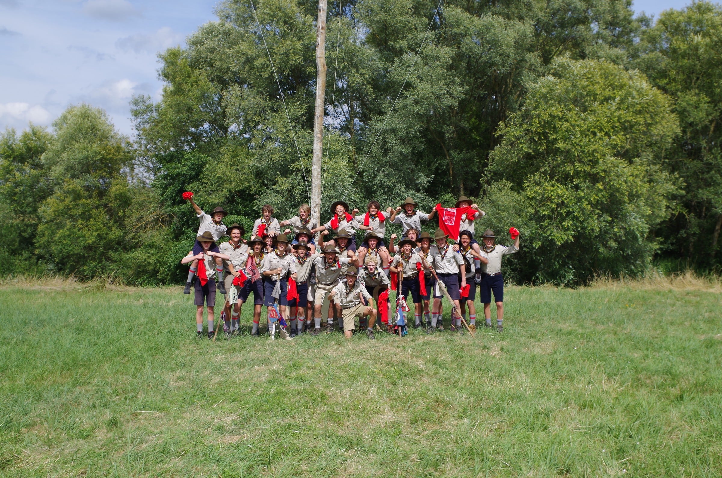 La Troupe en uniforme agite ses foulards devant le mât